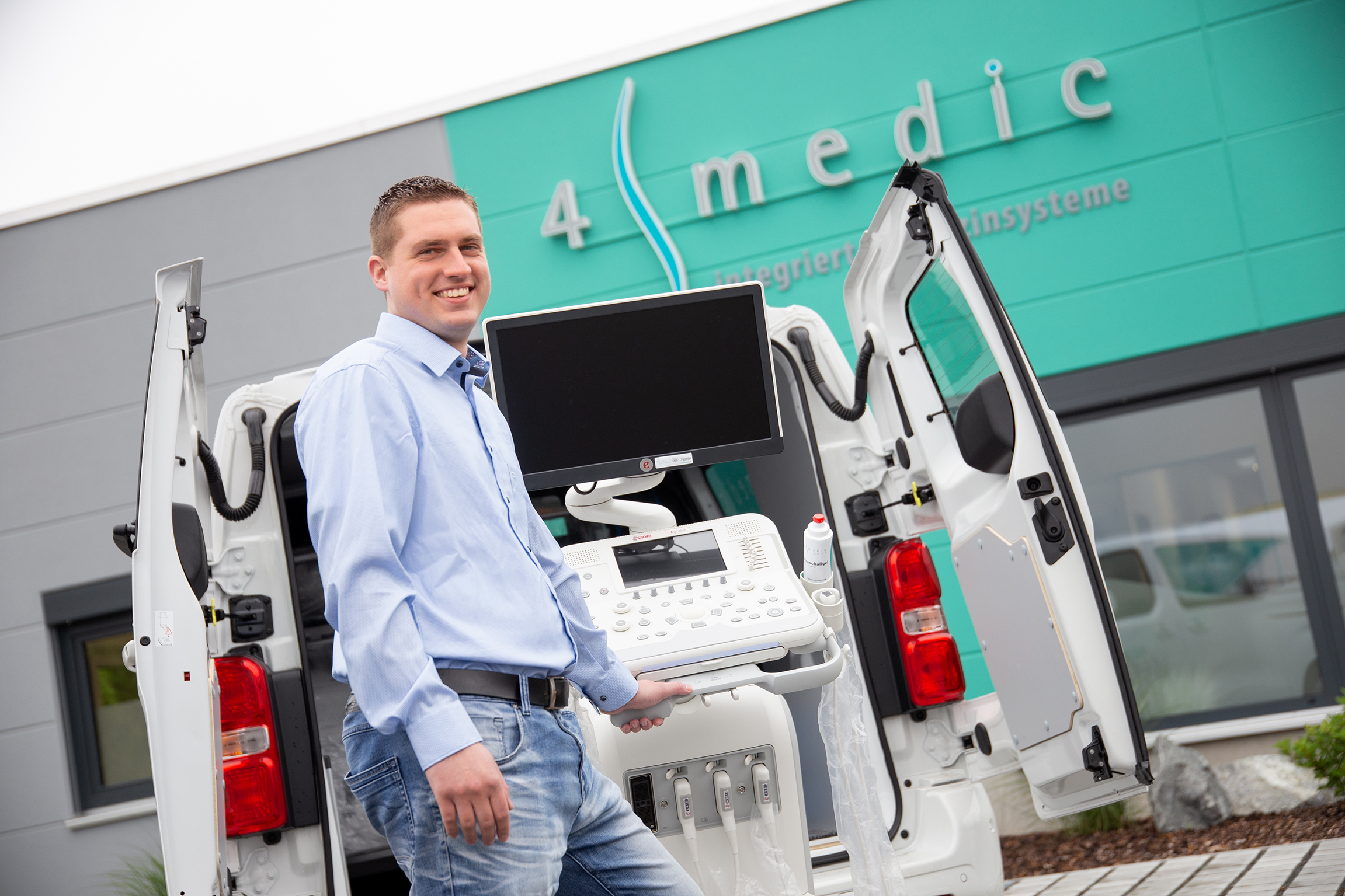 Mitarbeiter mit Ultraschallgerät vor 4medic Firmengebäude